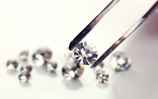 Beautiful shining crystal (diamond) in the tweezers, isolated